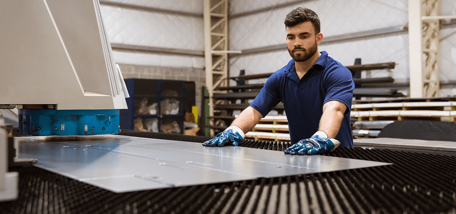 Technician processing metal sheet in workshop